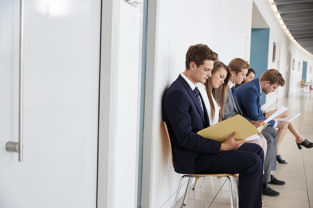 Job applicants sitting in a row while waiting for their turns to be interviewed.